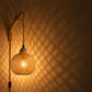 Bamboe wandlamp met snoer en schakelaar langs de muur, het licht tekent een ruitpatroon op de muur