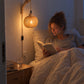 Vrouw leest 's avonds in bed bij het licht van de bamboe wandlamp naast haar hoofd